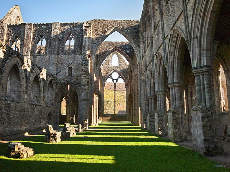 Interior of Tintern Abbey, with long shadows cast by the arcades.