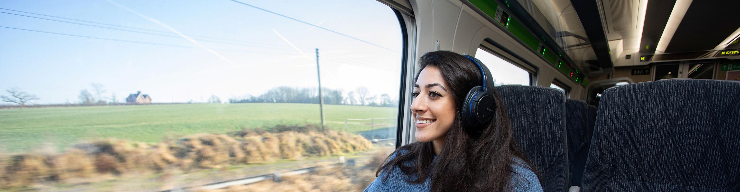 Customer sitting on GWR train looking outside window, listening to Window Seater app