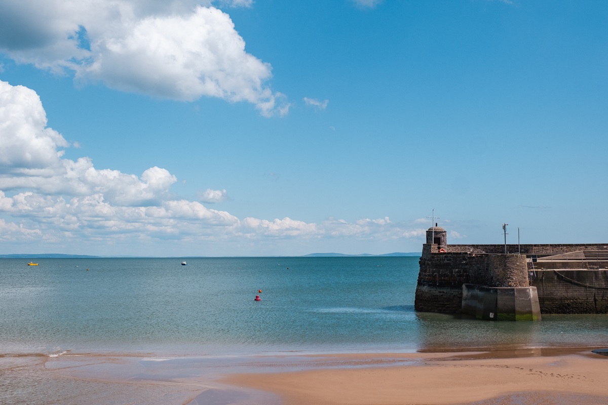 Saundersfoot beach with the sea expanding beyond the horizon, on a clear day.