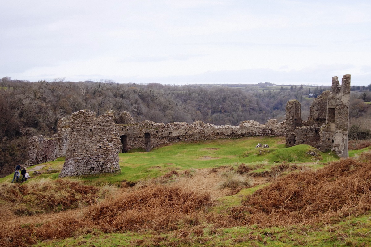 Wide shot of Pennard Castle, with two people dwarfed by the stones as they approach.