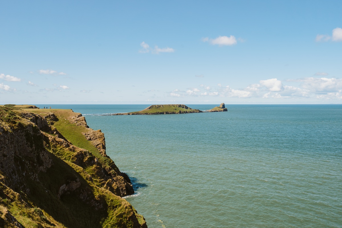 Wide shot of Rhossili Bay and Worm's Head on a clear and sunny day.