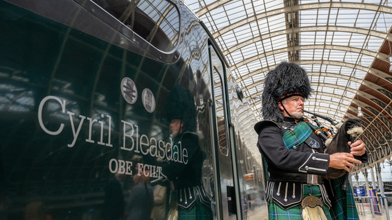 A lone piper leading a tribute, alongside a GWR train named in Cyril Bleasdale OBE's honour