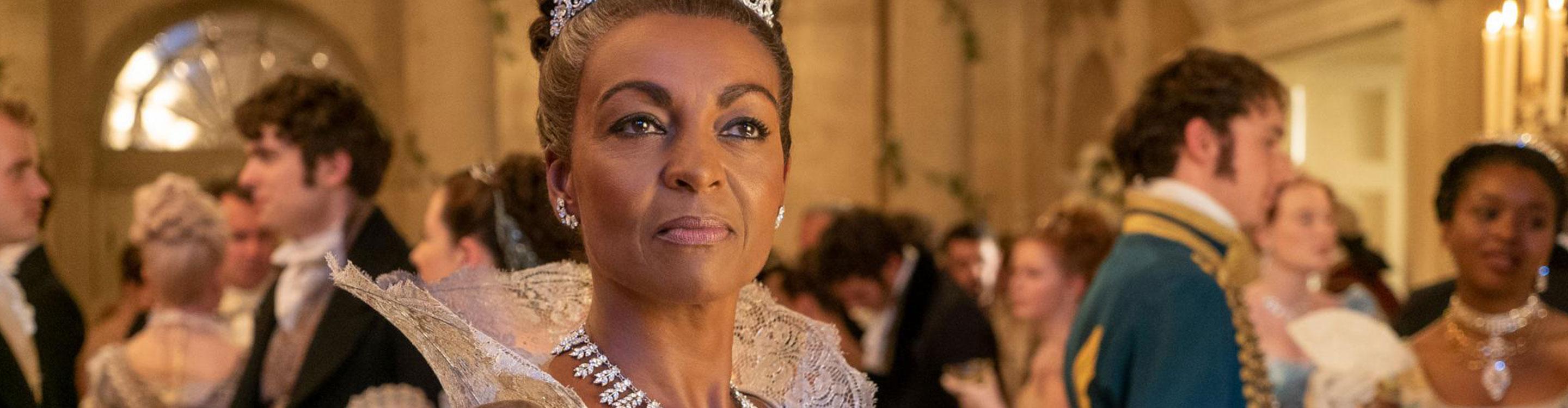 Adjoa Andoh performing as Lady Danbury in the Netflix series Bridgerton, seen here in a white ballgown and tiara, with guests in the background, filmed on location in Bath, Somerset, UK