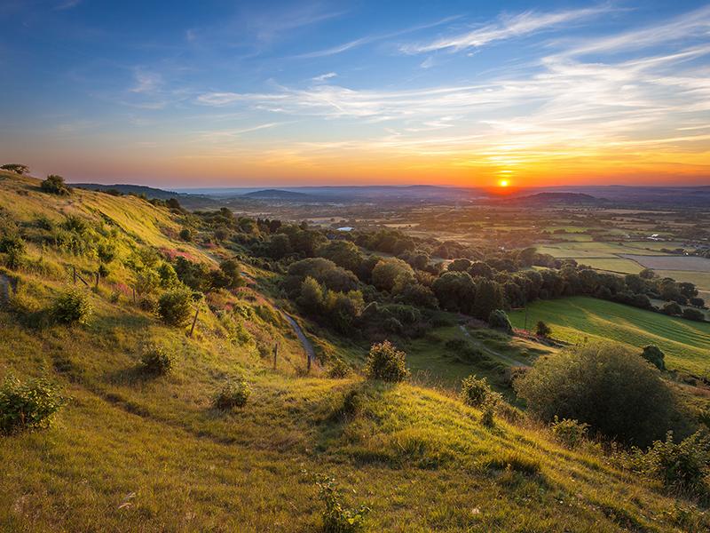 Rolling hills of the Cotswolds with sun setting in background