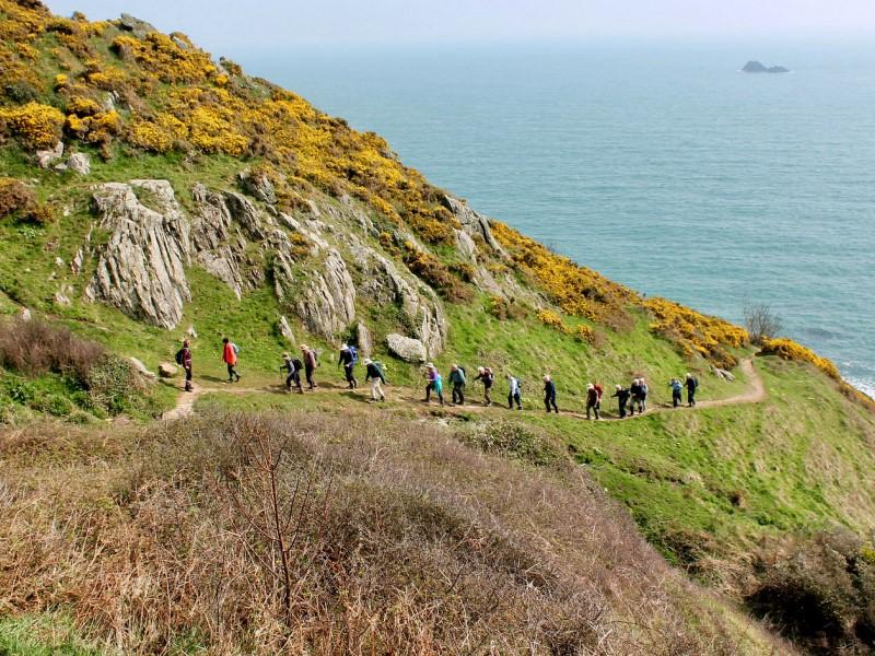 A group of people hiking through the South West Coast Path.