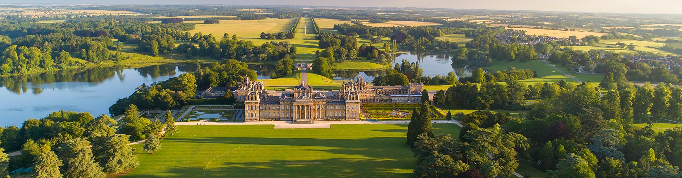 Long shot of Blenheim Palace on a fine summer day, with vibrant greenery framing the landscape surrounding the Palace.
