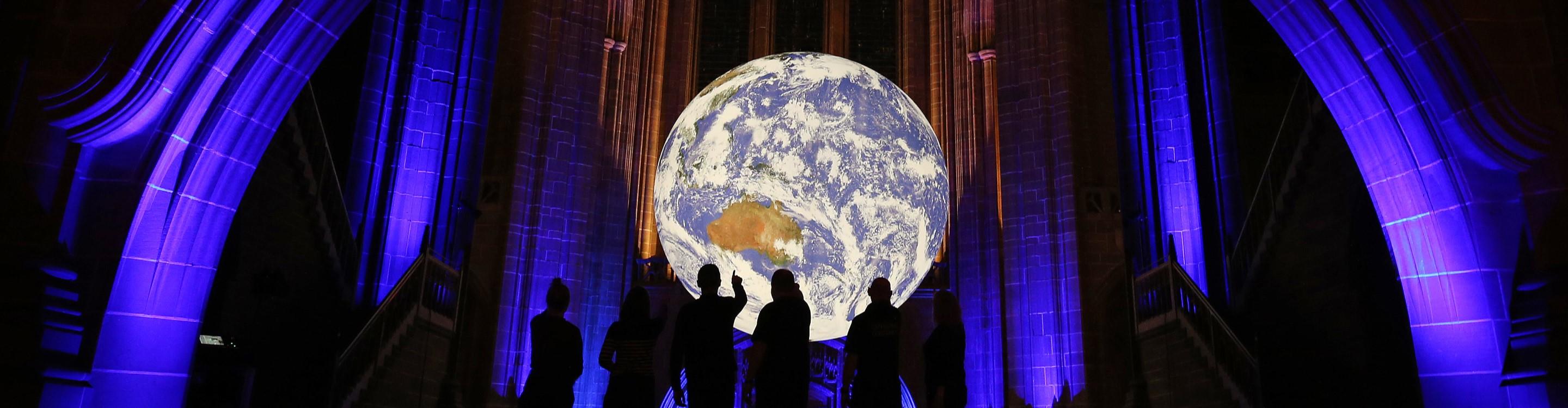 Silhouette of people staring at the illuminated Gaia exhibition