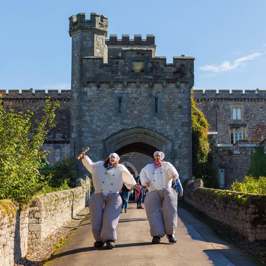 Two people dressed in oversized, inflated chef's whites in front of Powderham Castle, to celebrate Powderham Food Festival