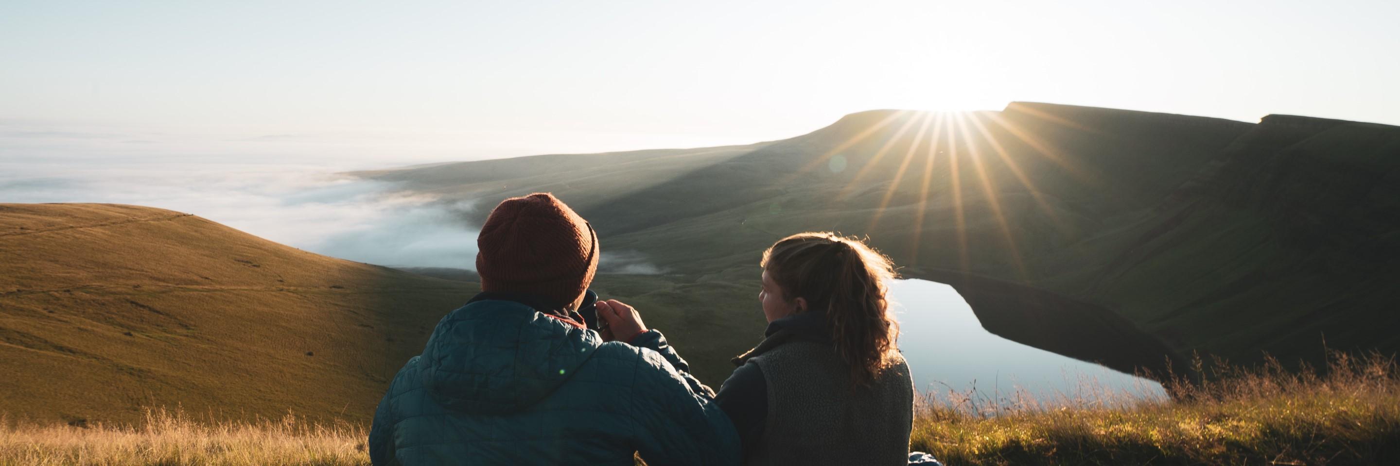 Photo of two people watching a sunset over Llyn y Fan Fach