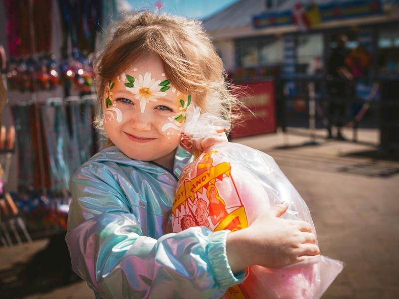 Photo of a child with facepaint, clutching a bag of candy floss on the Grand Pier at Weston-super-Mare