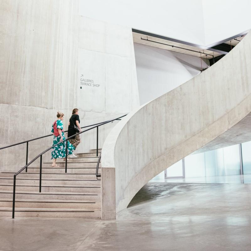 Two people climbing the stairs at an art gallery