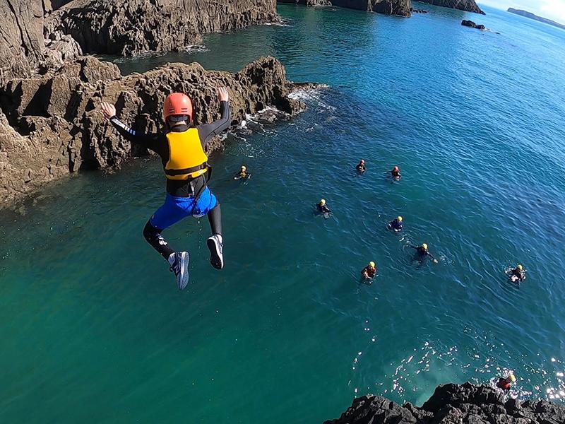 Coasteering jumping off a cliff into the sea