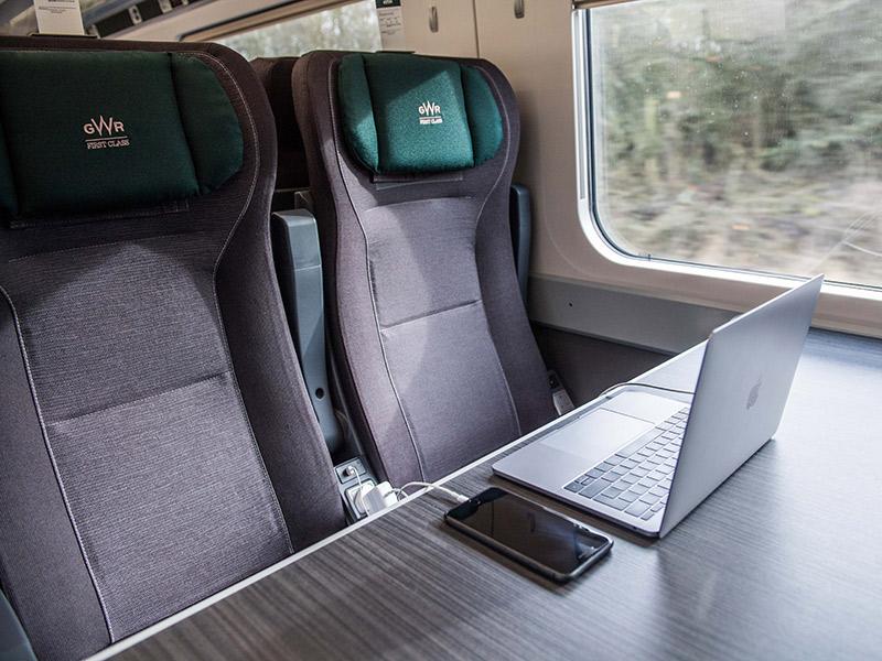 Two seats in a GWR First Class carriage, with laptop and mobile phone on the table. 