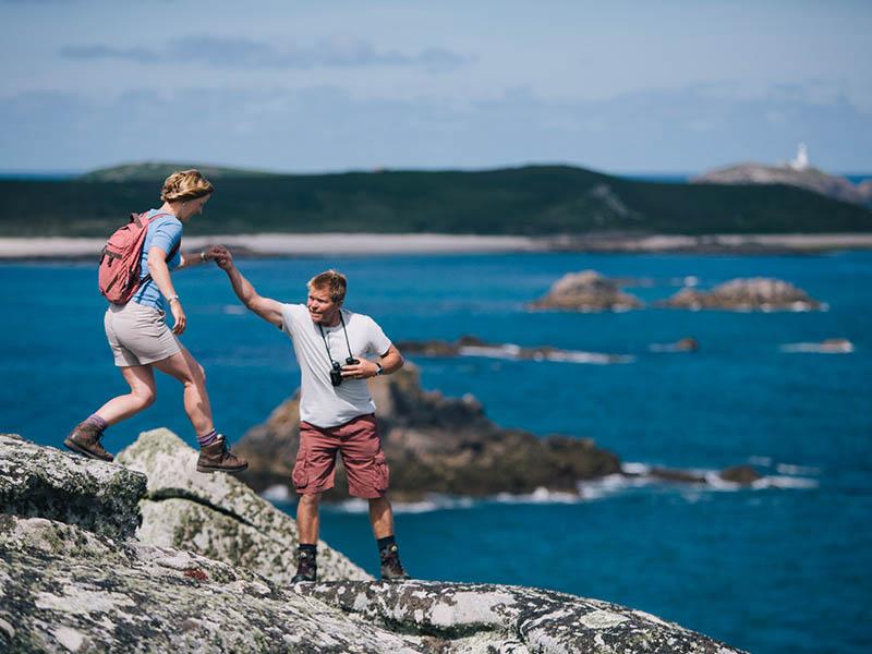 Couple climbing in from of ocean view at the Isles of Scilly