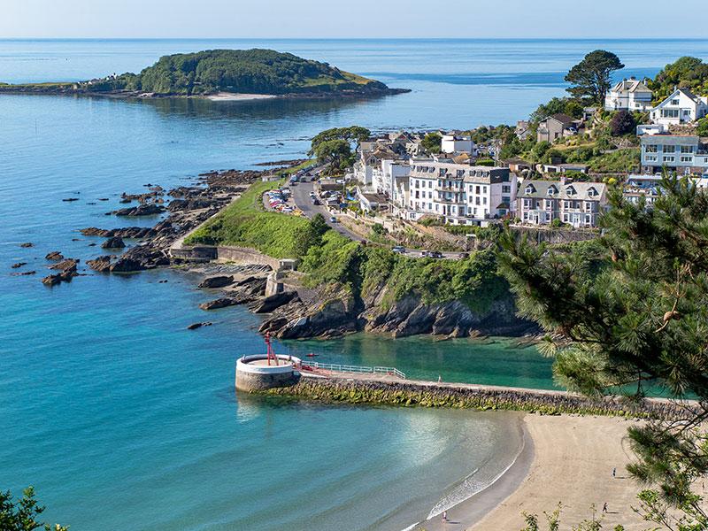 Elevated view of Looe Beach, Banjo Pier, Hannafore, with white buildings set in the trees, and Looe Island, Looe, Cornwall, UK