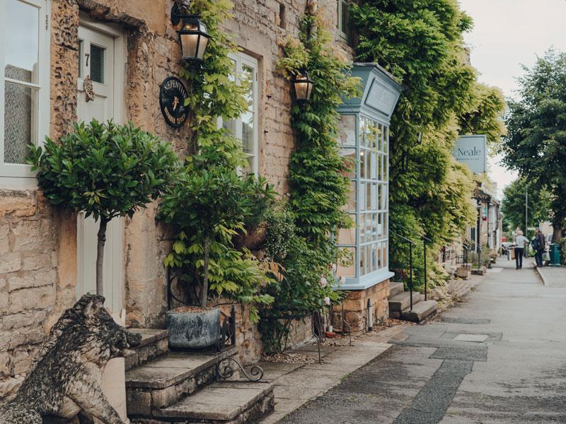 Row of houses on a main street in Stow-on-the-Wold, some local residents on the background. Stow is a market town in Cotswolds, UK