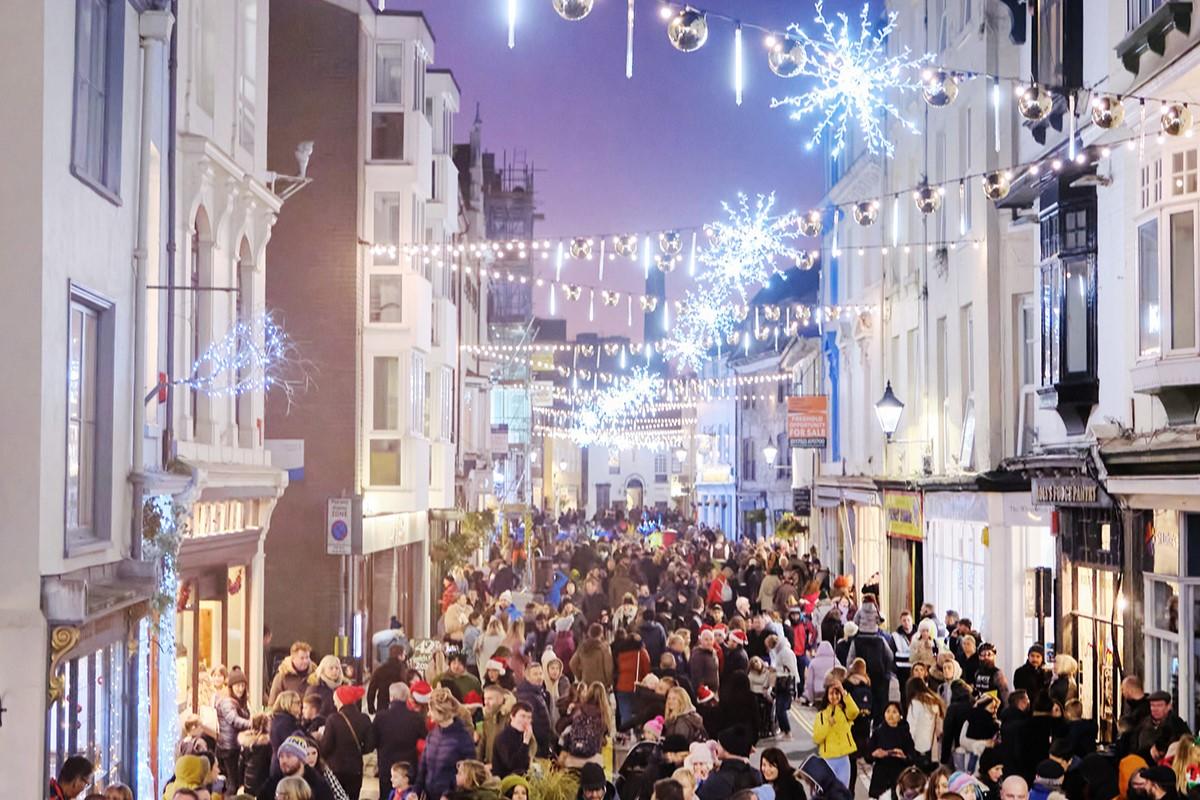 Crowds walking through a street in Plymouth at Christmas, with Christmas lights illuminated above them