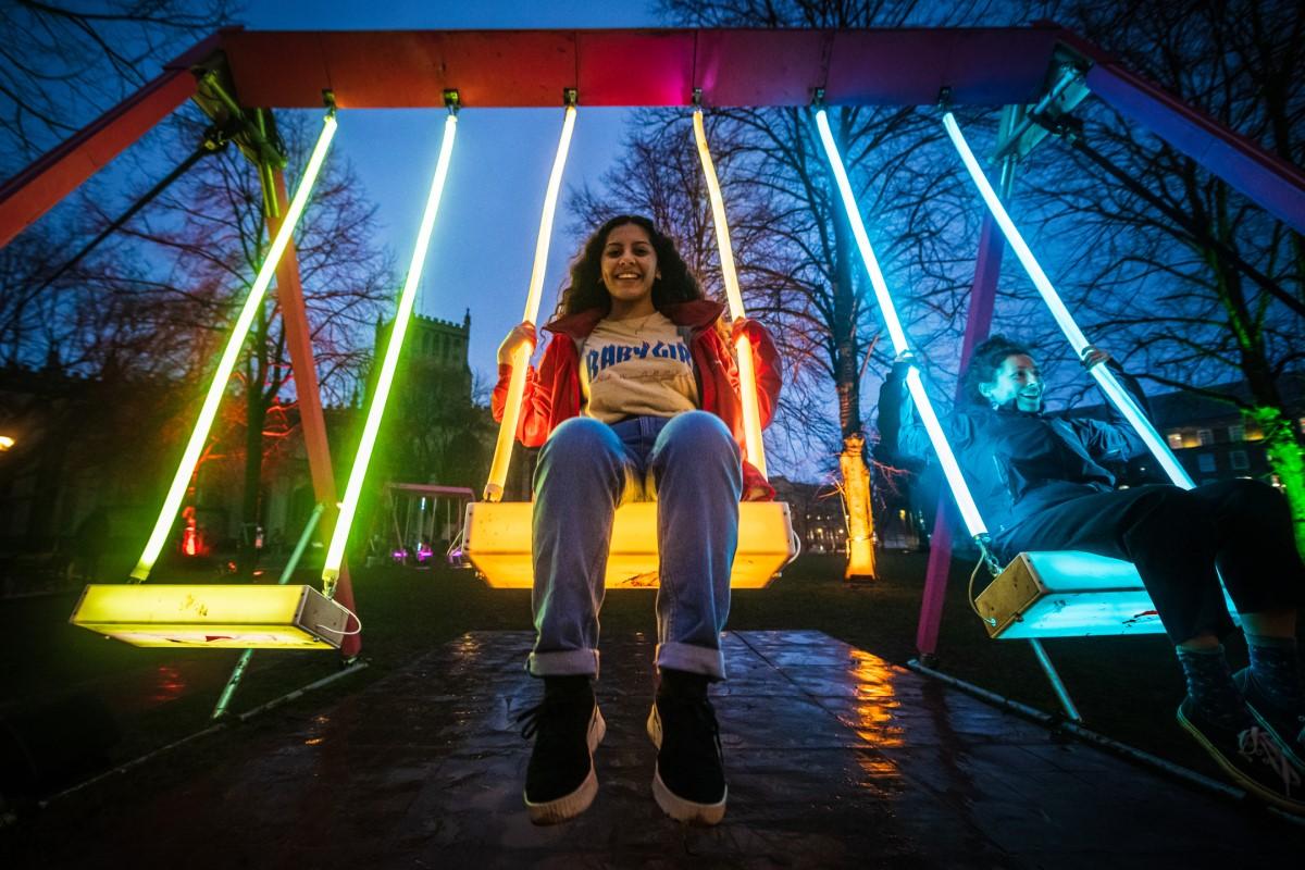A young person on an illuminated swing set at the Bristol Light Festival